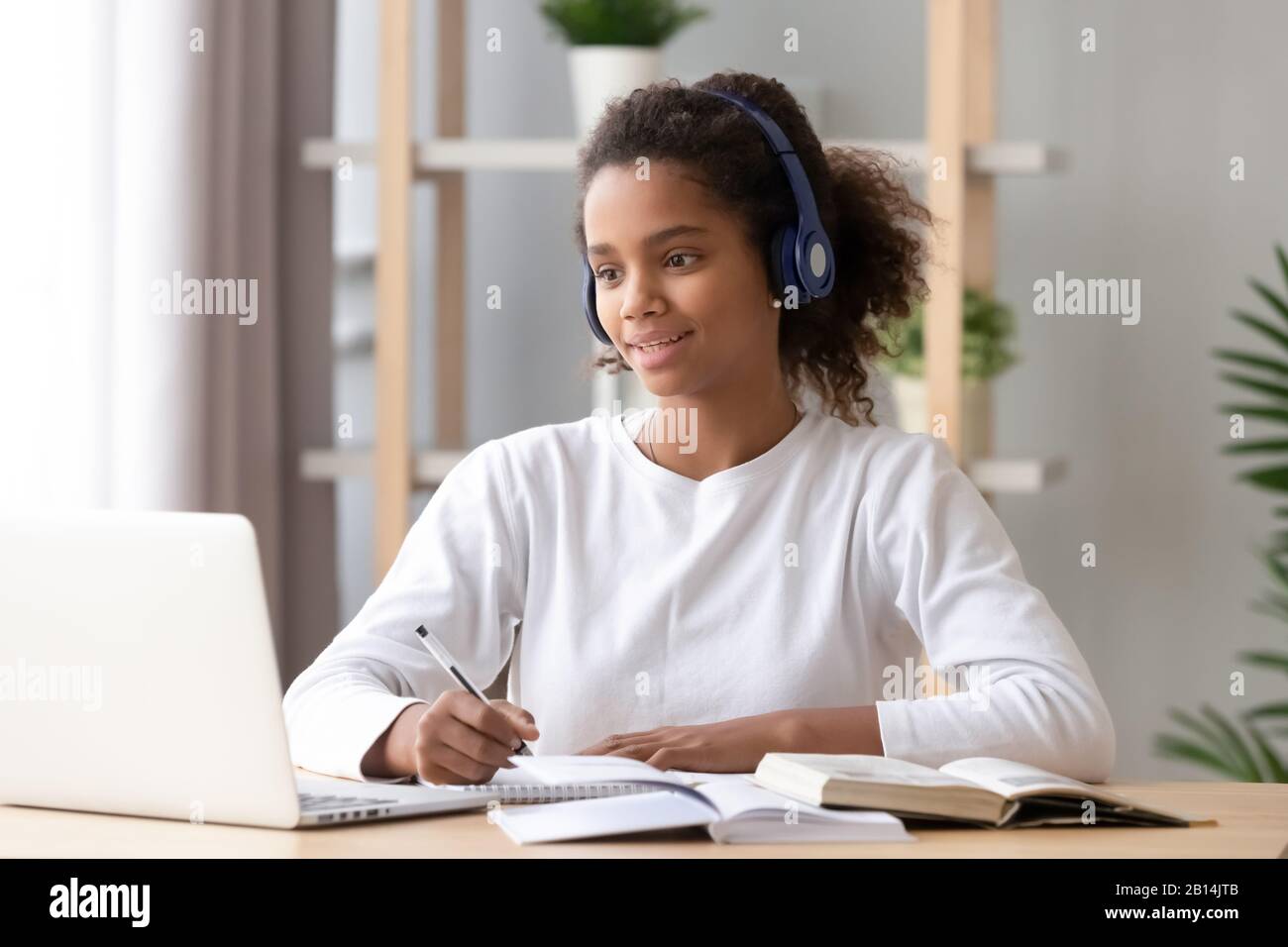 Une fille africaine portant un casque d'étude avec un professeur skype sur un ordinateur portable Banque D'Images