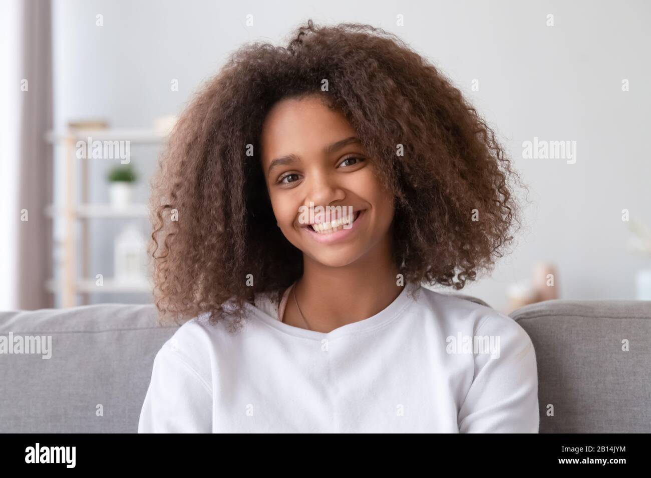 Headshot de fille africaine souriante regardant l'appareil photo à la maison Banque D'Images