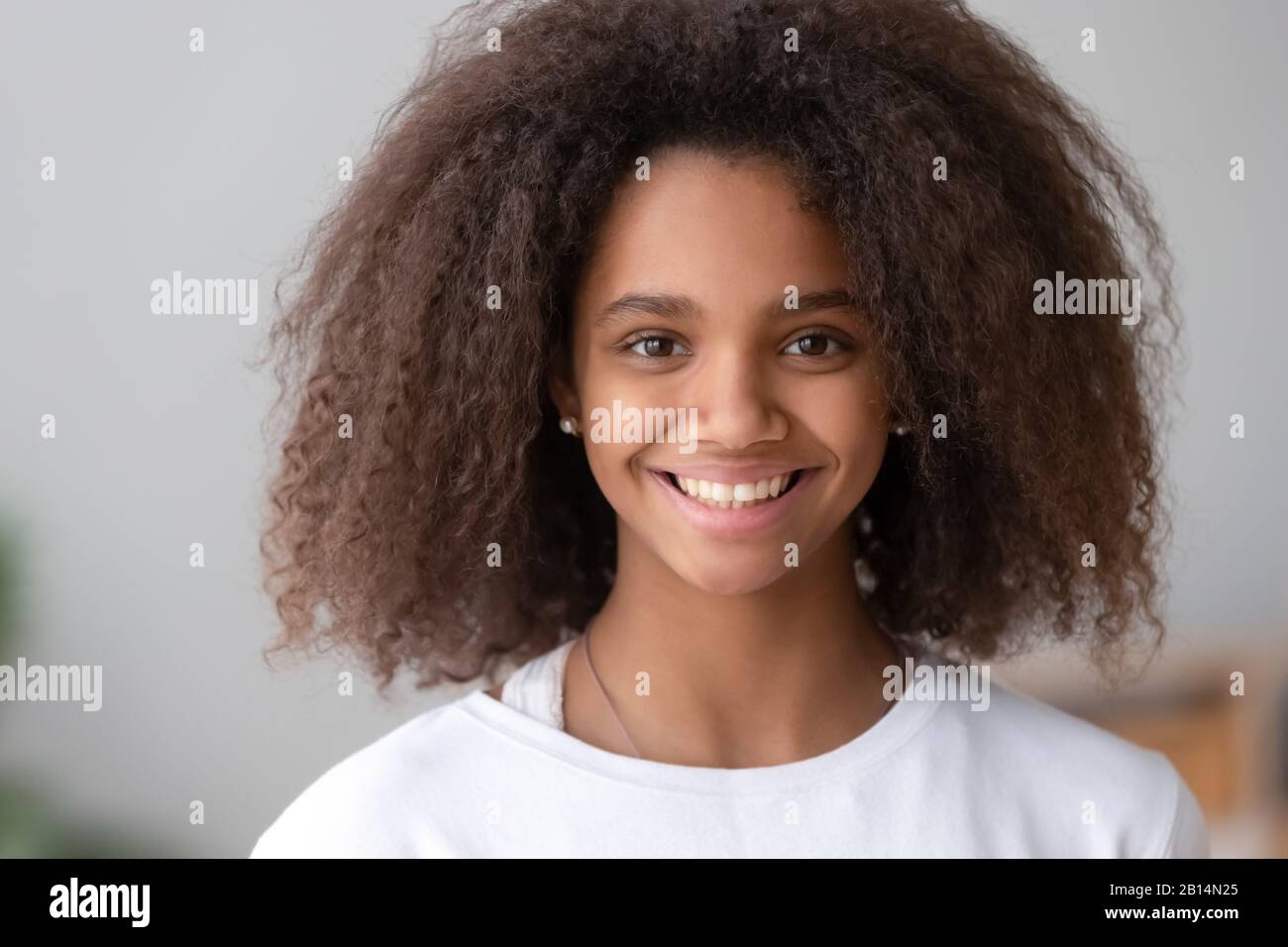 Tête de mignonne fille adolescente africaine souriante regardant l'appareil photo Banque D'Images