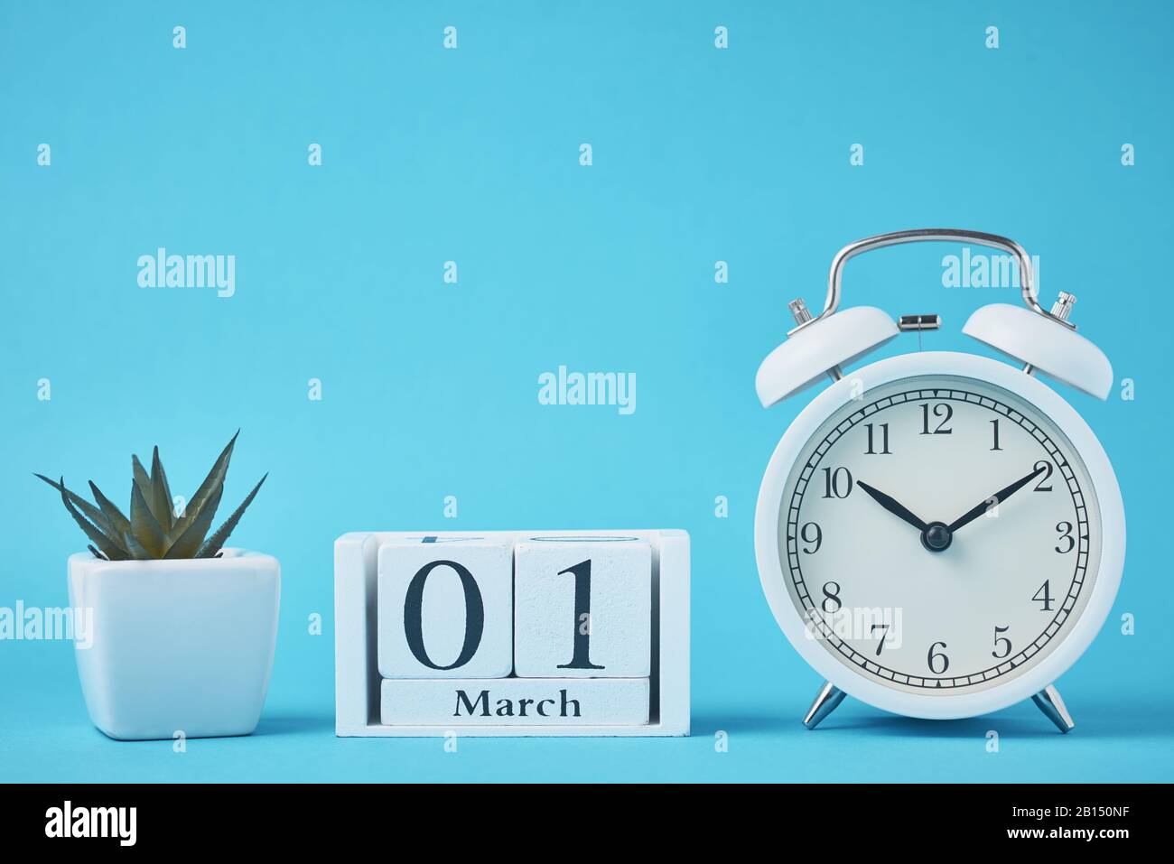 Réveil rétro blanc avec cloches et blocs calendrier en bois avec date du 1er mars sur fond bleu Banque D'Images