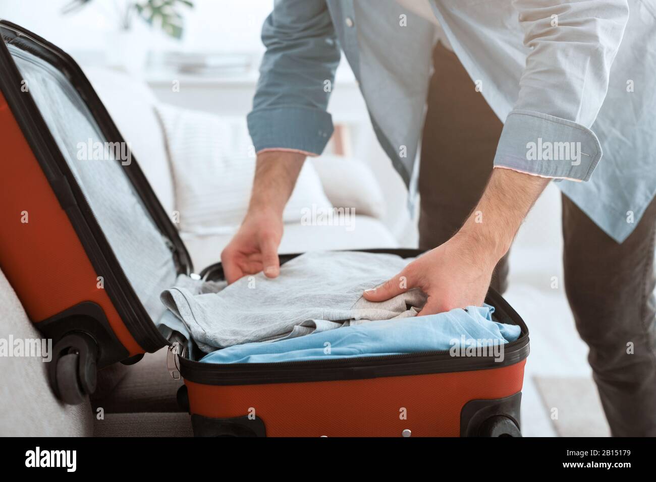Préparation du voyage. Guy emballe des vêtements dans la valise Banque D'Images