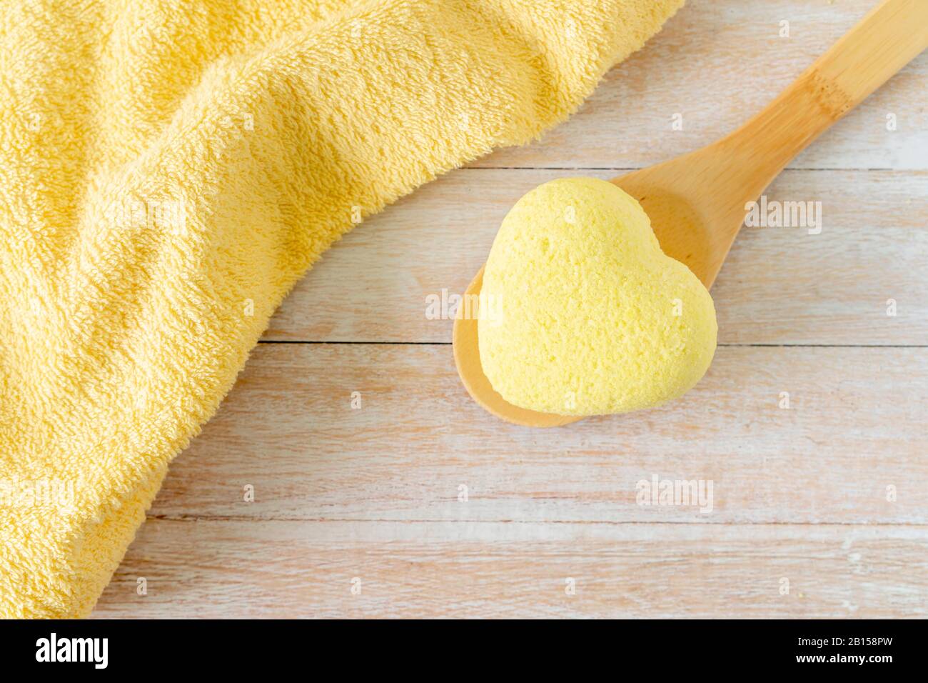 Composition du bain à remous avec bombes de bain dans la forme de coeur, sel de mer, serviettes pour la beauté et le traitement du corps. Relaxation saine, aromathérapie, soins du corps et massage aromatique sur fond en bois. Bain naturel et douche concept cosmétique. Banque D'Images