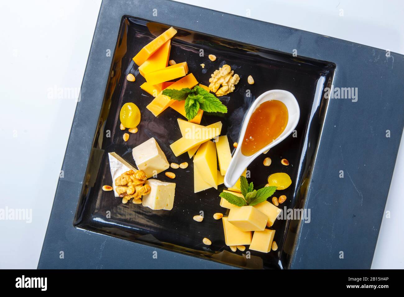 Assiette à fromage - morceaux de différents types de fromage avec noix et miel. Sur fond blanc. La vue du haut. Banque D'Images