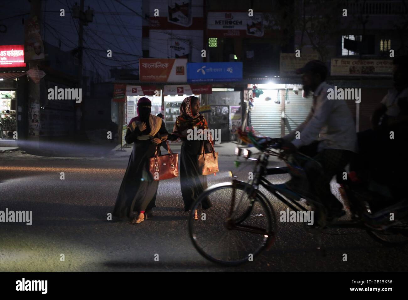 Dhaka, Bangladesh. 23 février 2020. Un extracteur de pousse-pousse passe alors que deux femmes traversent une route poussiéreuse pendant le coucher du soleil à Dhaka. Selon l'indice de la qualité de l'air, Dhaka est la deuxième ville la plus défavorable au monde. Crédit: Md Mehedi Hasan/Zuma Wire/Alay Live News Banque D'Images