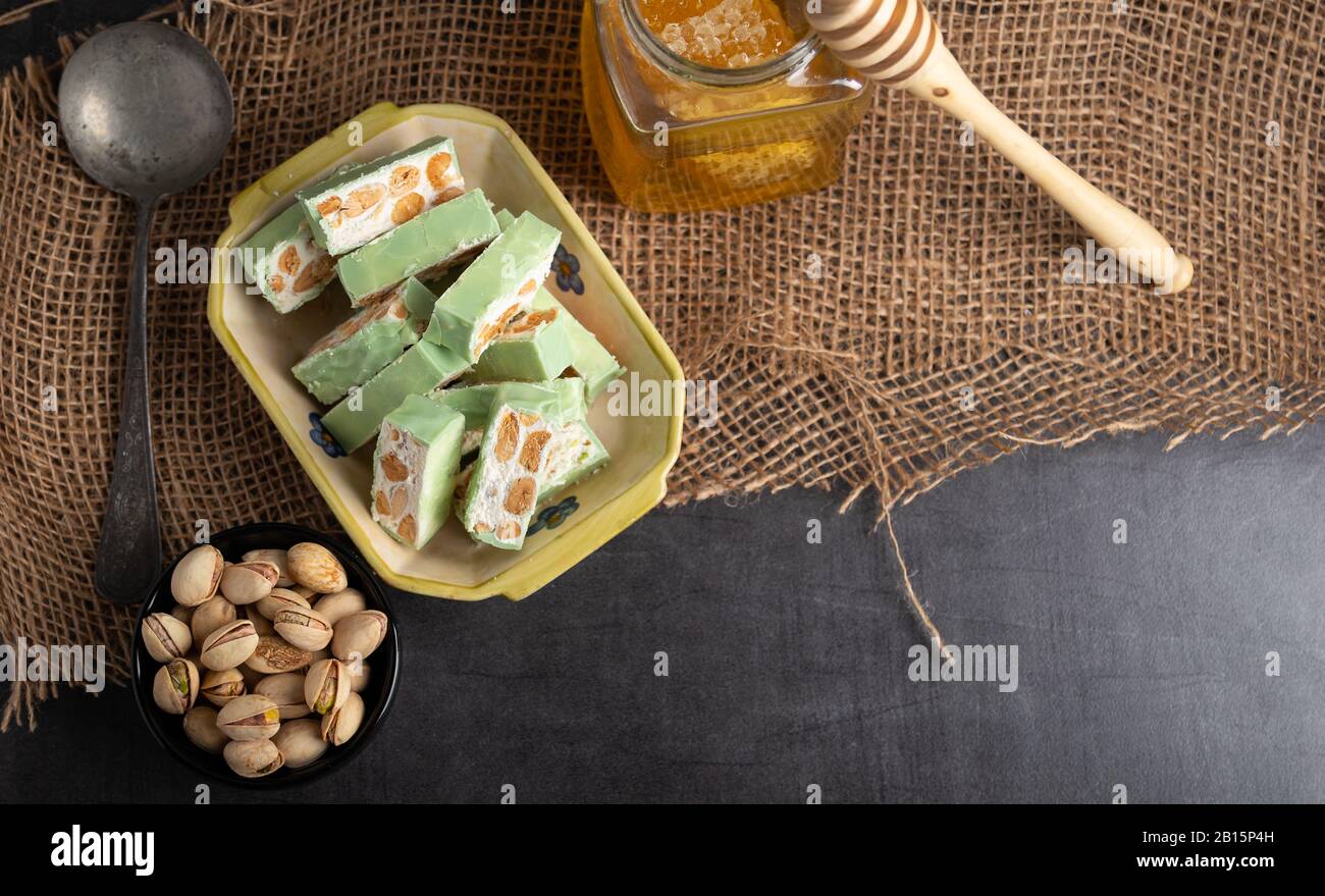 Nougat bio faites avec du miel, pistache, noisette, noix et amandes, sur un fond sombre. rustique Banque D'Images