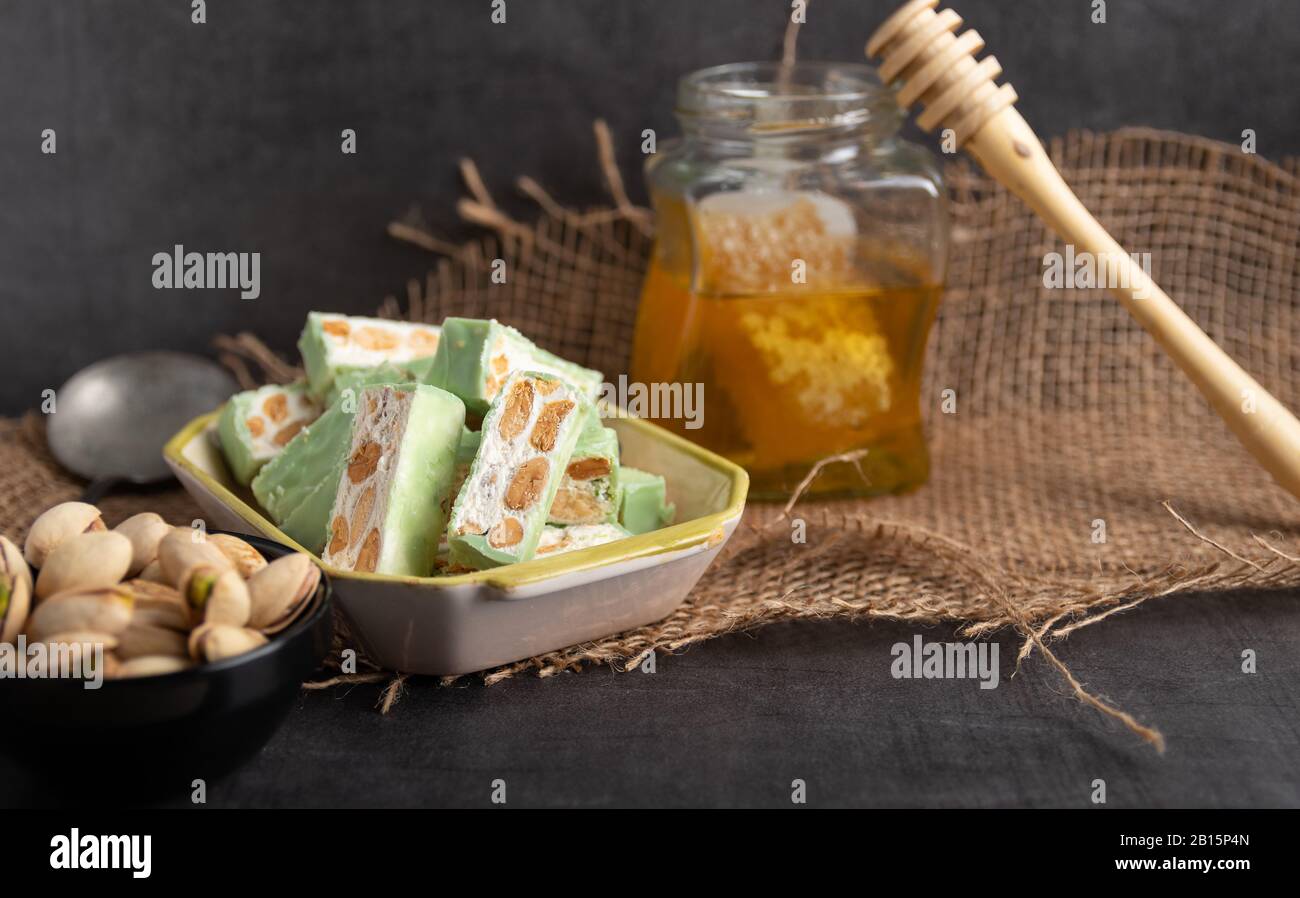 Nougat bio faites avec du miel, pistache, noisette, noix et amandes, sur un fond sombre. rustique Banque D'Images