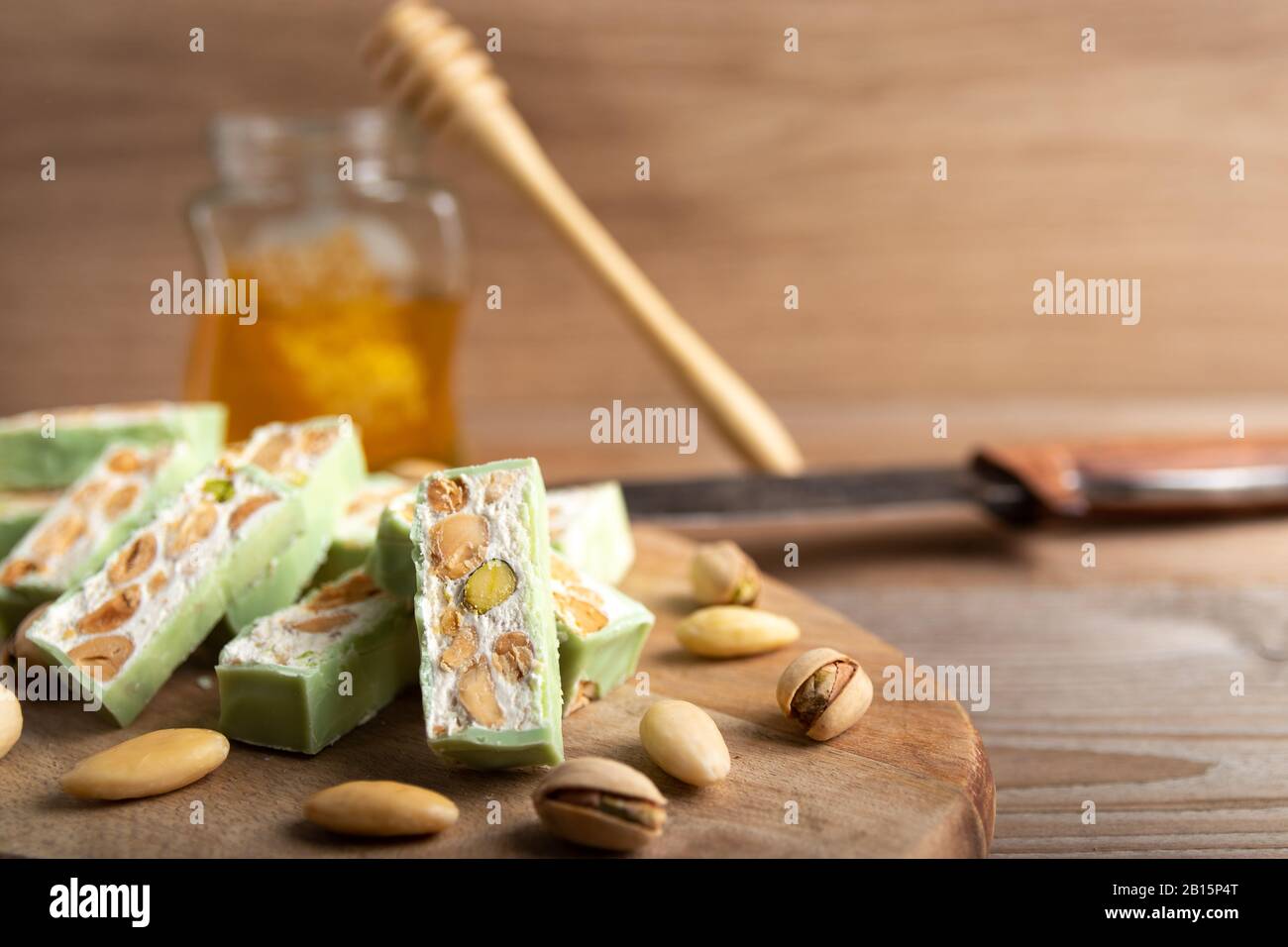 Nougat bio faites avec du miel, pistache, noisette, amande et noix sur une table en bois en arrière-plan. Banque D'Images