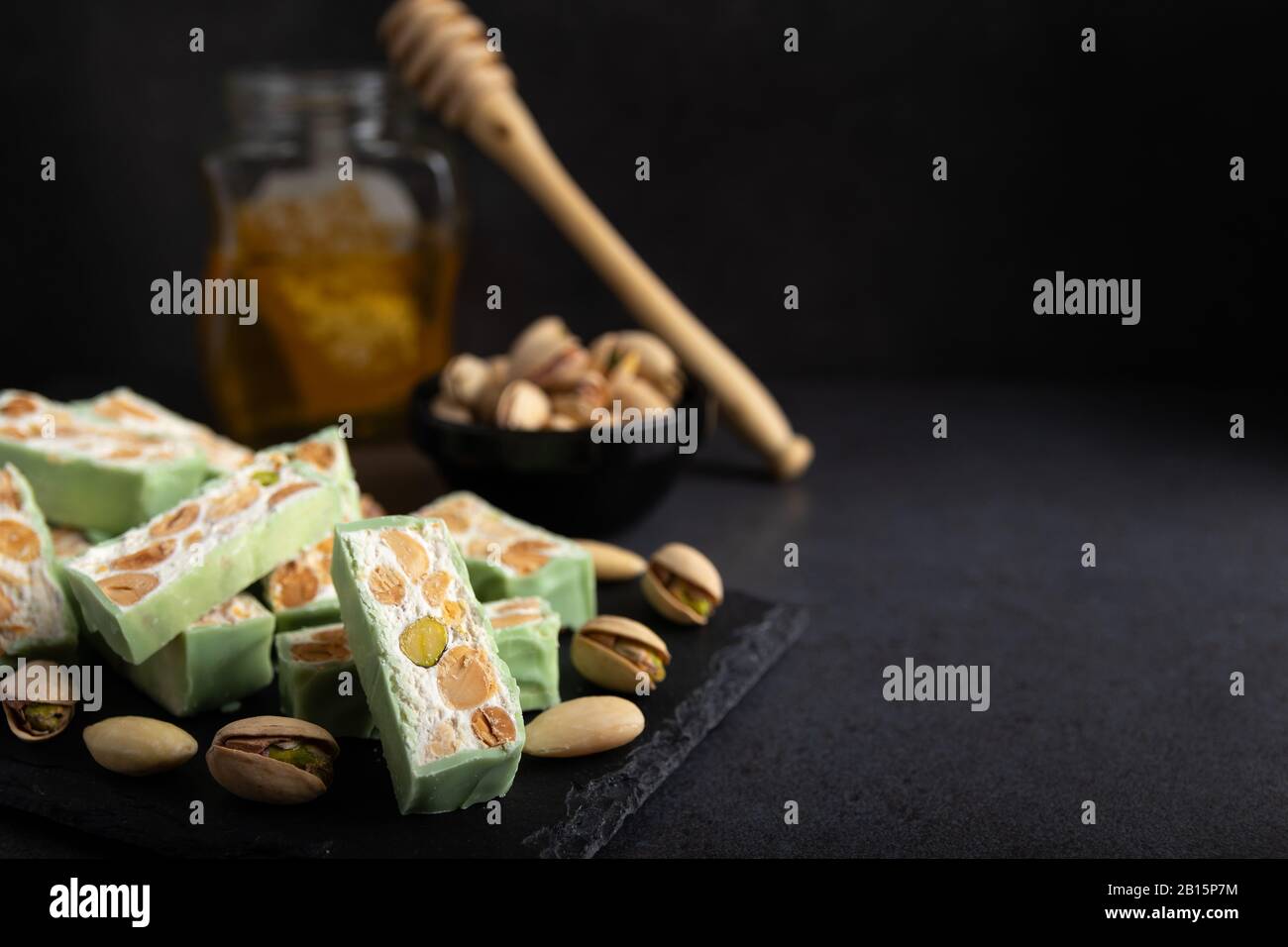 Nougat bio faites avec du miel, pistache, noisette, noix et amandes, sur un fond sombre. rustique Banque D'Images