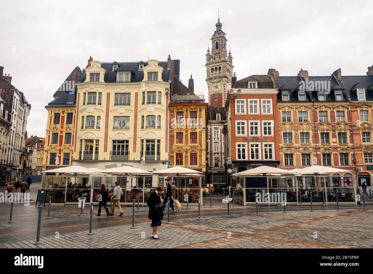 Même lors d'une journée de pluie, de superbes façades du XVIIe au XXe siècle donnent de la couleur à la place principale de Lille. Une vieille dame traverse cette « Grand Place ». Banque D'Images