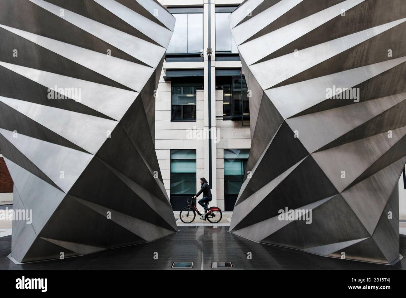 Photographie urbaine de Londres : le cycliste passe Paternoster vents, une sculpture en acier inoxydable de Thomas Heatherwick. Ville de Londres, Royaume-Uni Banque D'Images