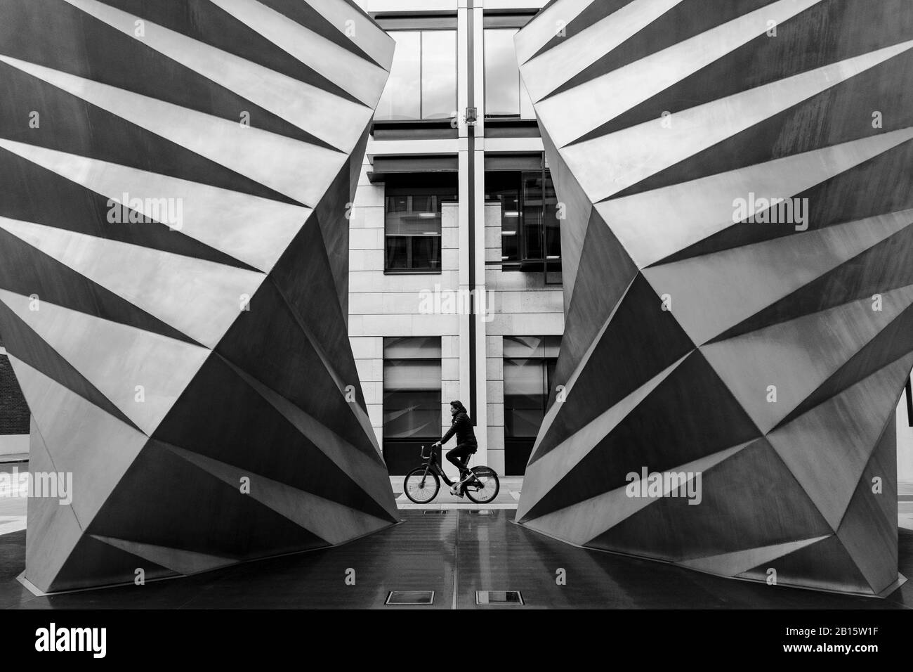 Photographie urbaine noir et blanc de Londres : le cycliste passe Paternoster vents, une sculpture en acier inoxydable de Thomas Heatherwick. Ville de Londres, Royaume-Uni Banque D'Images