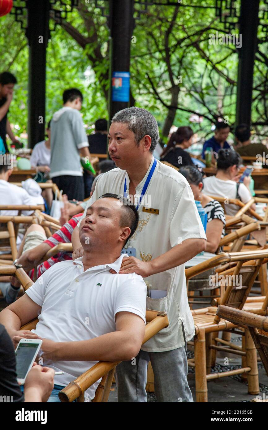 Homme chinois offrant un massage relaxant des épaules dans le Chengdu People's Park China Banque D'Images