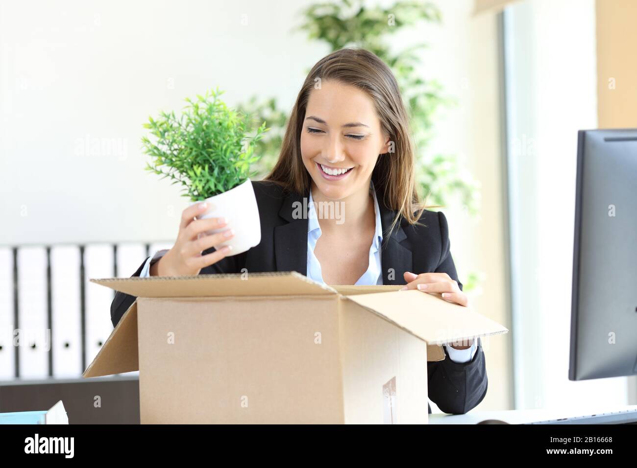 Une femme d'affaires heureuse retirer ses affaires de la boîte pour obtenir un nouveau travail au bureau Banque D'Images