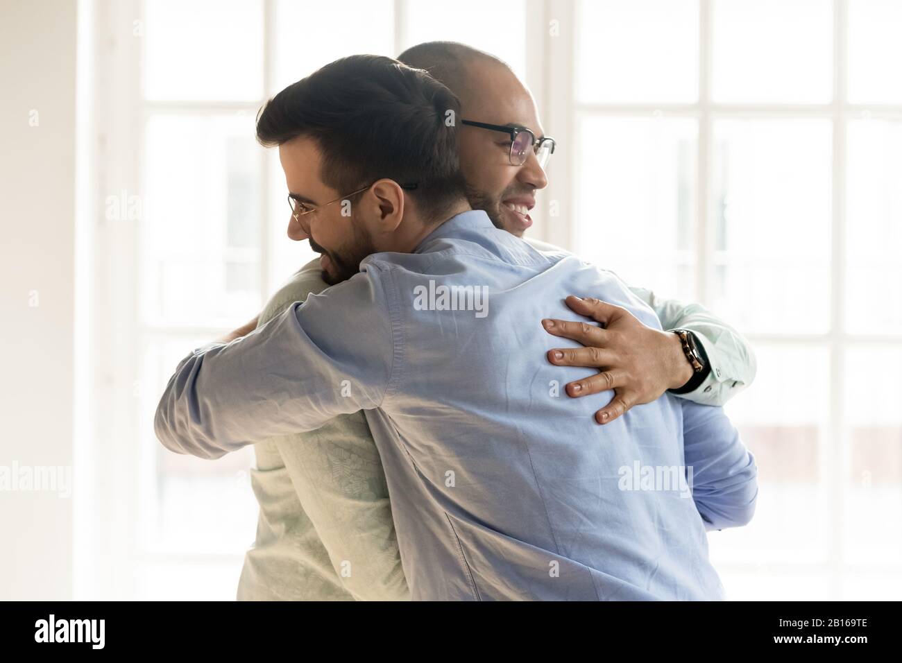 Les gars africains et caucasiens embrassent heureux de se voir mutuellement Banque D'Images