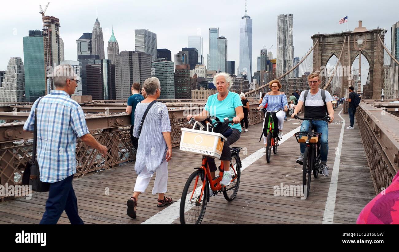 Cyclistes et piétons traversant le pont de Brooklyn avec les gratte-ciel de Manhattan en arrière-plan Banque D'Images