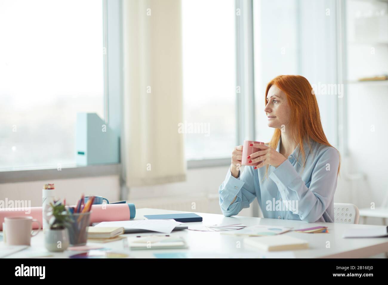 Vue latérale portrait de la jeune femme imprudente rêvant un jour au bureau moderne tout en buvant du café sur le lieu de travail, espace de copie Banque D'Images