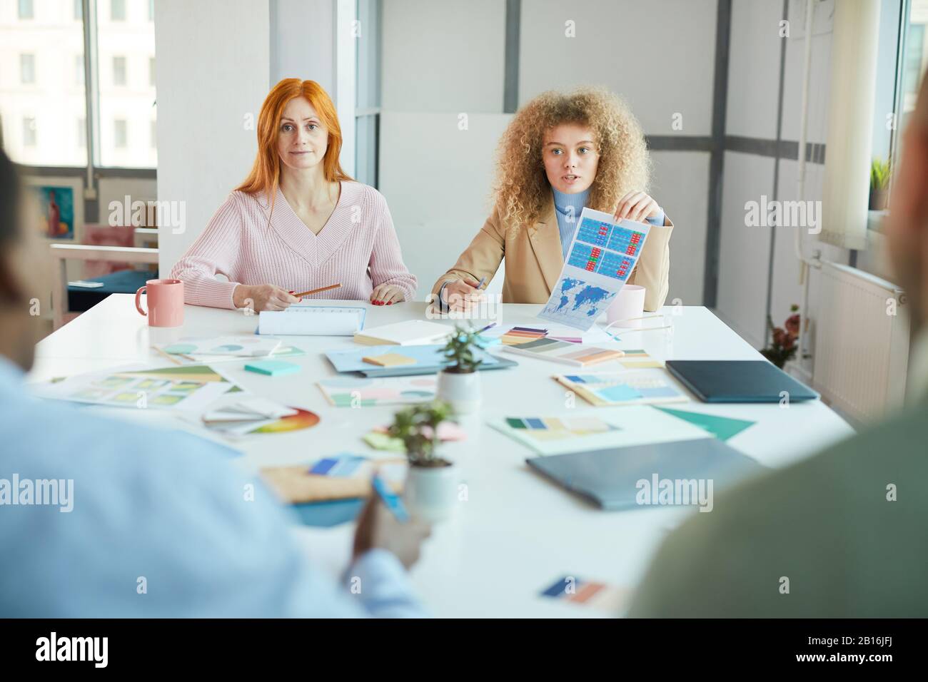 Portrait de deux femmes d'affaires assis en face de deux hommes tout en discutant du projet de travail, espace de copie Banque D'Images