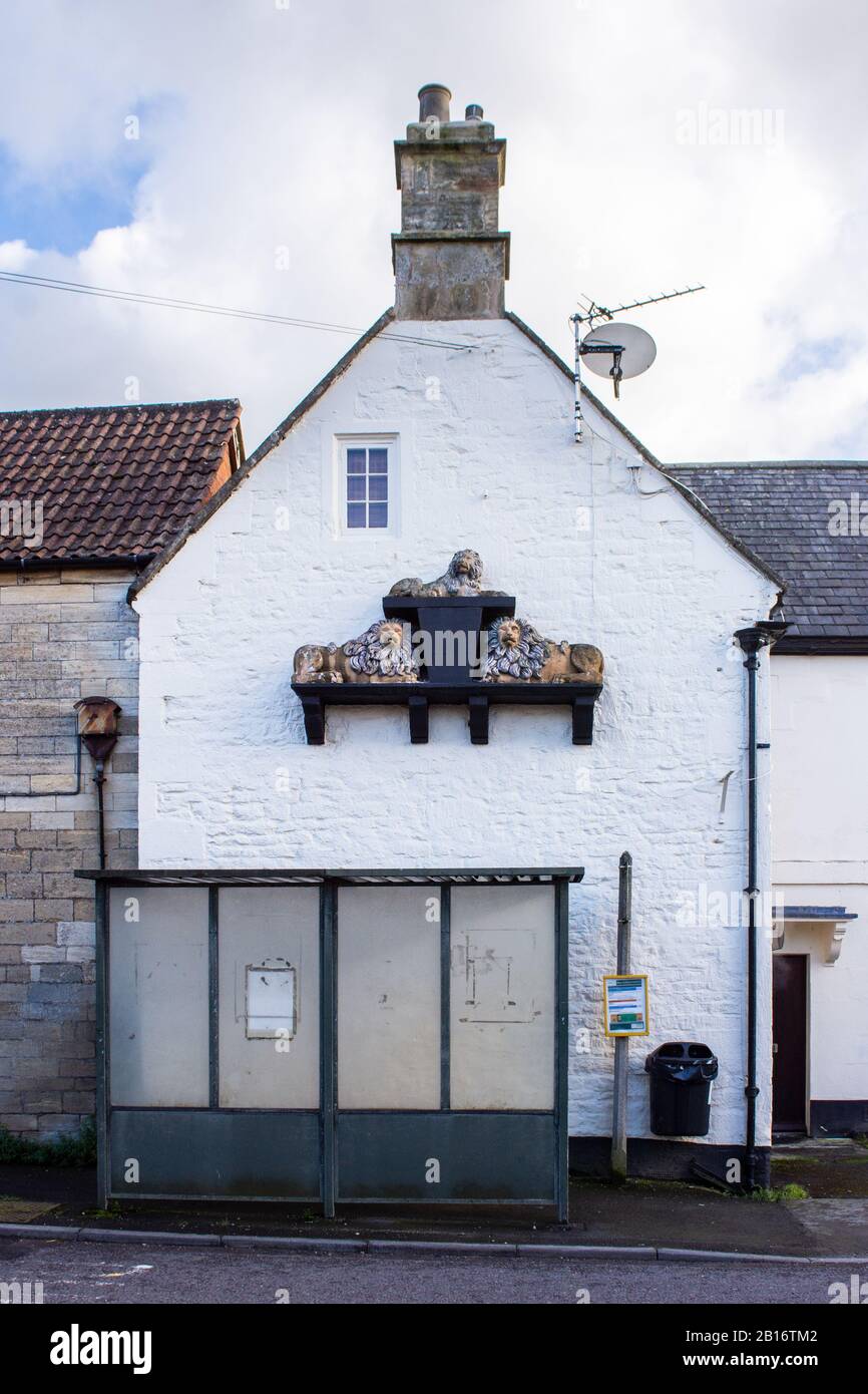 3 lions une sculpture projetant à partir d'un mur de ce qui était autrefois un pub appelé les 3 lions avec un abri d'arrêt de bus en face dans le village de Holt à Wilt Banque D'Images