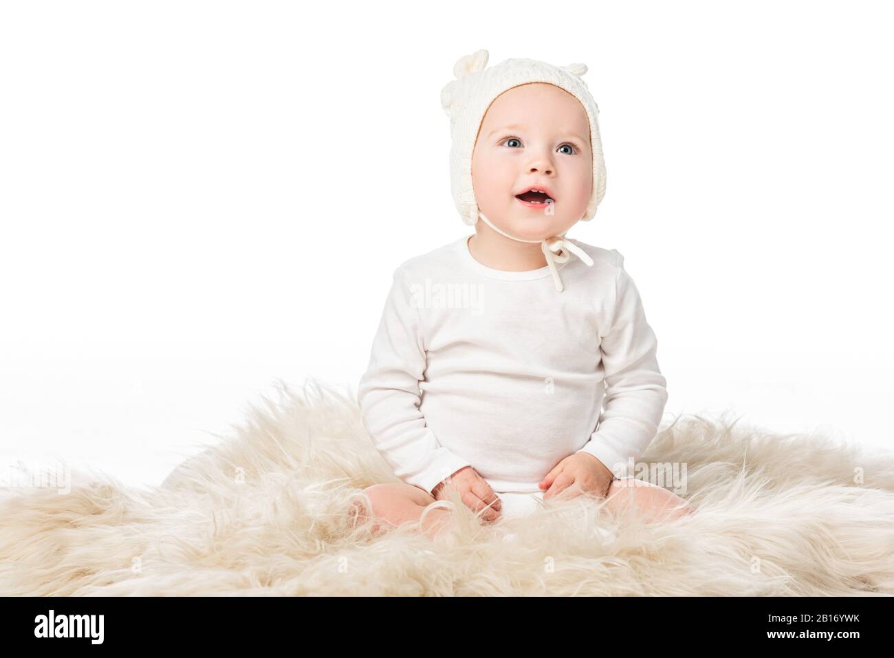 Enfant portant un bonnet de bébé, tenant l'oeuf de pâques à bouche ouverte,  assis sur une fourrure isolée sur blanc Photo Stock - Alamy