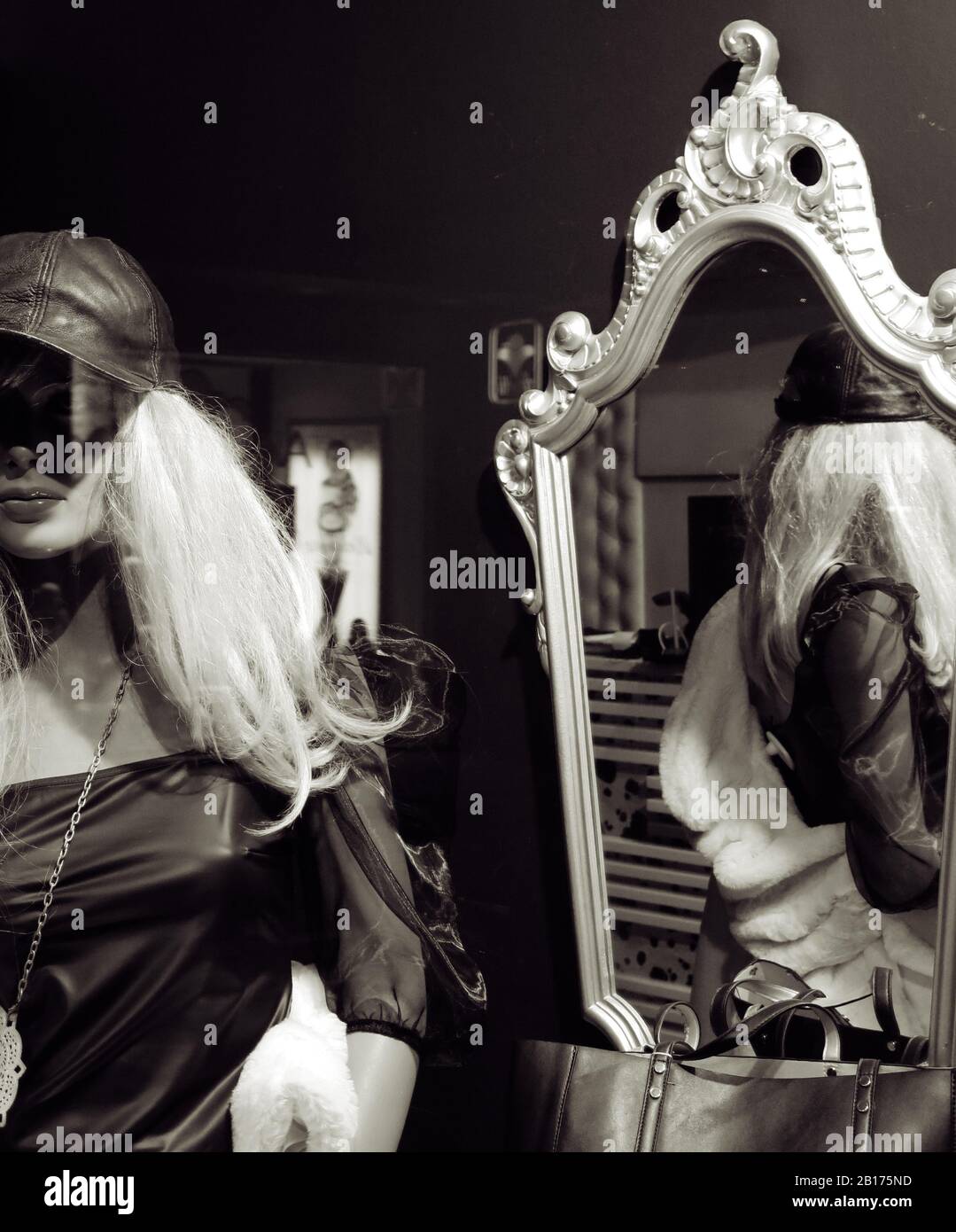 Mannequin féminin réfléchi sur un miroir vintage dans une fenêtre de magasin. Banque D'Images