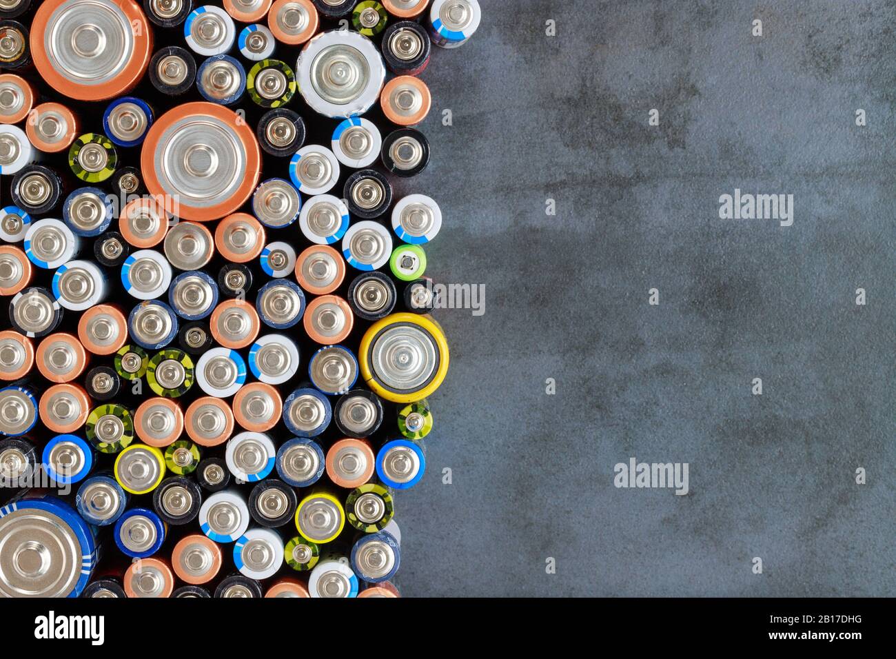 Gros plan sur les extrémités positives des batteries déchargées colorées de différents formats et tailles, vue de dessus, espace de copie. Pile alcaline utilisée sur fond noir Banque D'Images