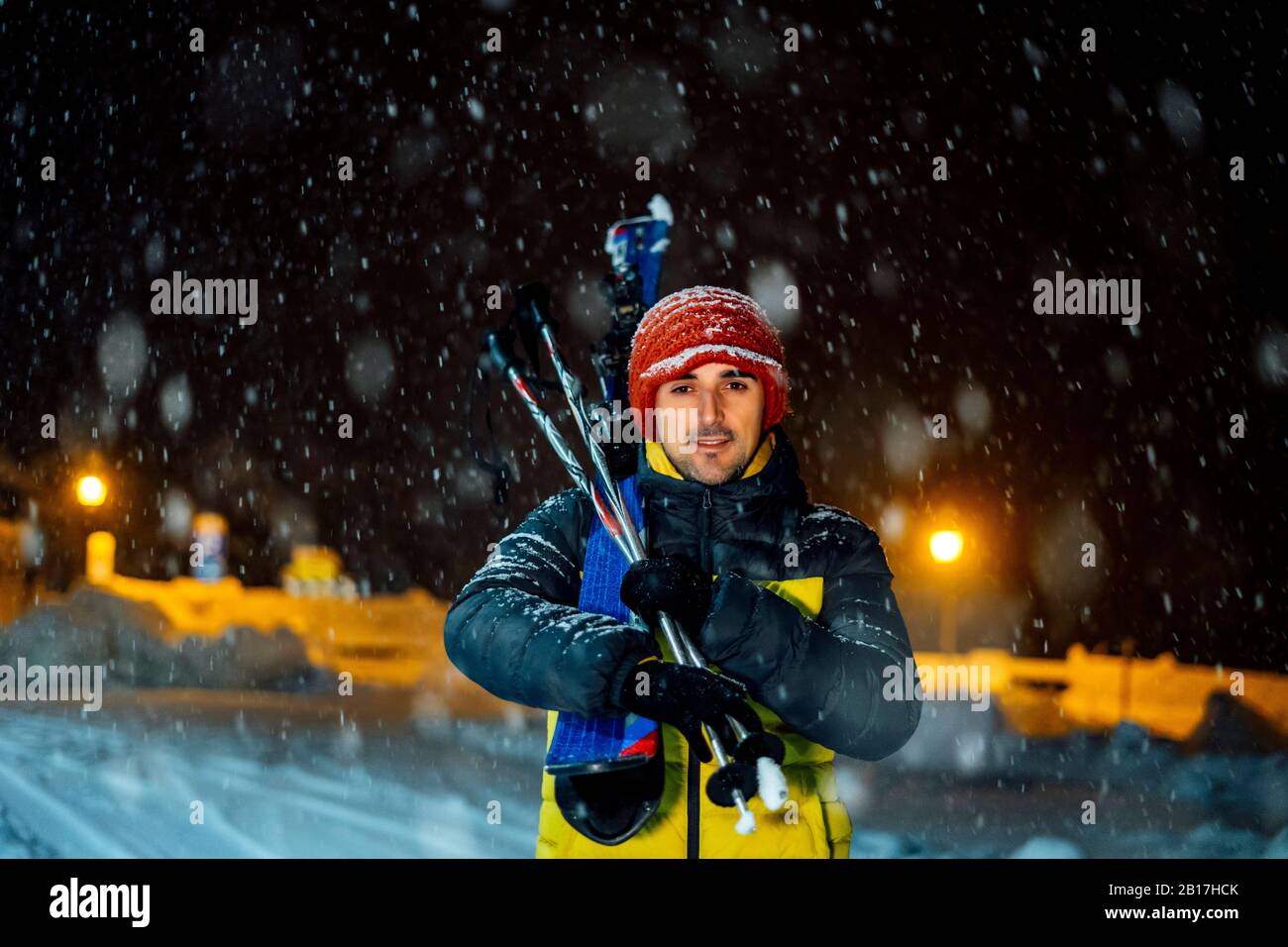 Portait de l'homme avec des skis dans la neige la nuit Banque D'Images