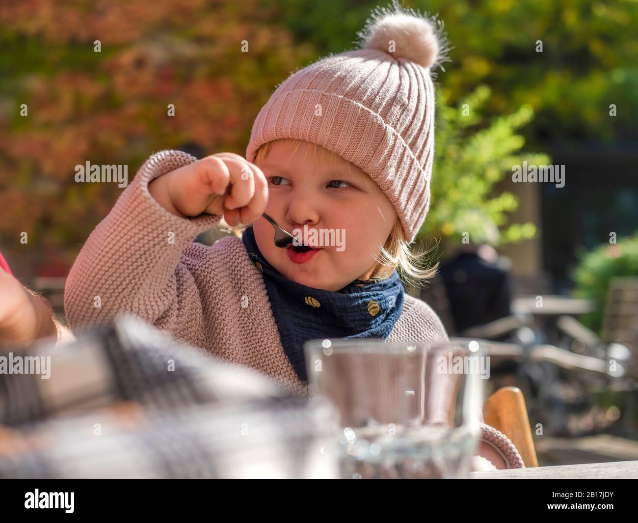 Portrait de la jeune fille qui mange au café extérieur en automne Banque D'Images