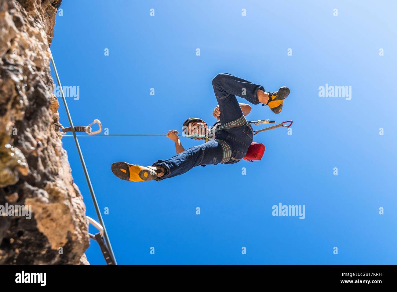 Un grimpeur souriant s'asseyant du visage de rock Banque D'Images