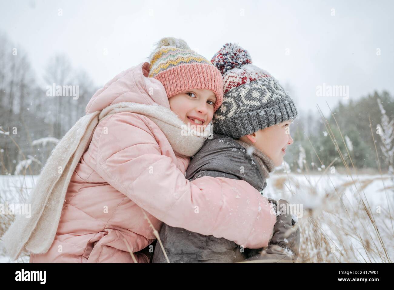 Garçon donnant à sa petite sœur une balade en porcgyback dans la forêt d'hiver Banque D'Images