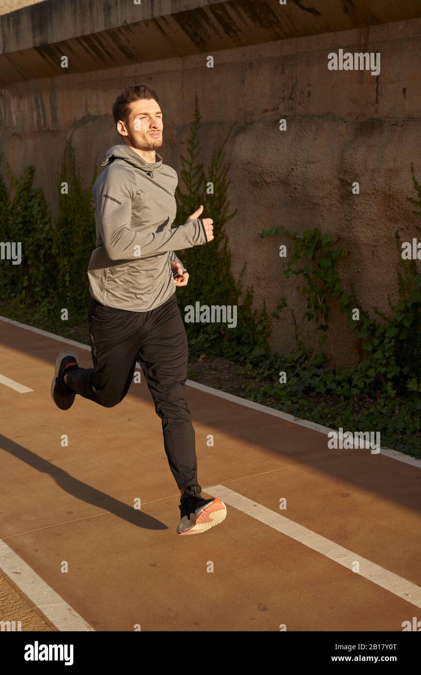 Homme qui courir sur une route en plein soleil Banque D'Images