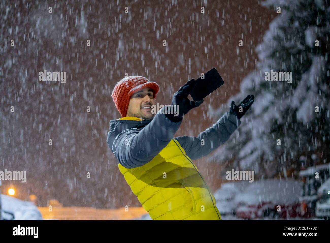 Homme souriant prenant un selfie en neige la nuit Banque D'Images