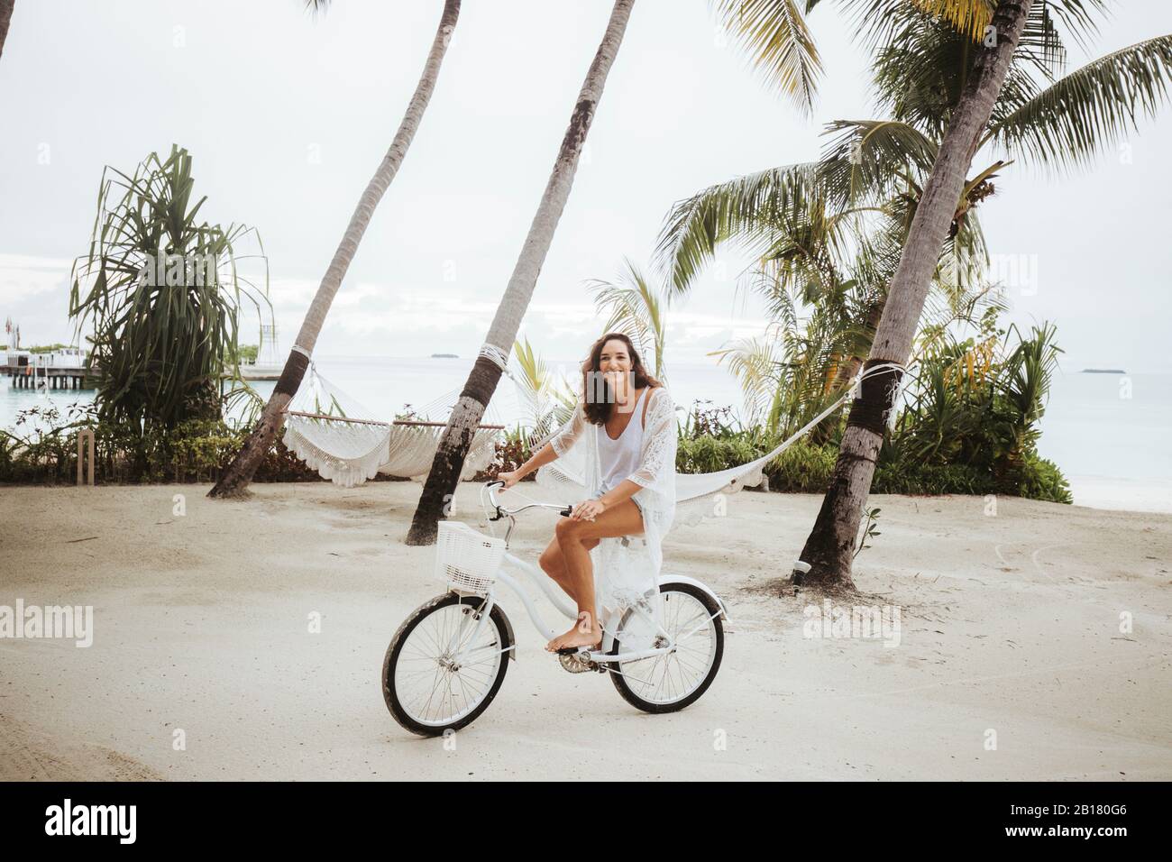 Femme à vélo sur la plage, île de Maguhdhuvaa, atoll de Gaafu Dhaalu, Maldives Banque D'Images