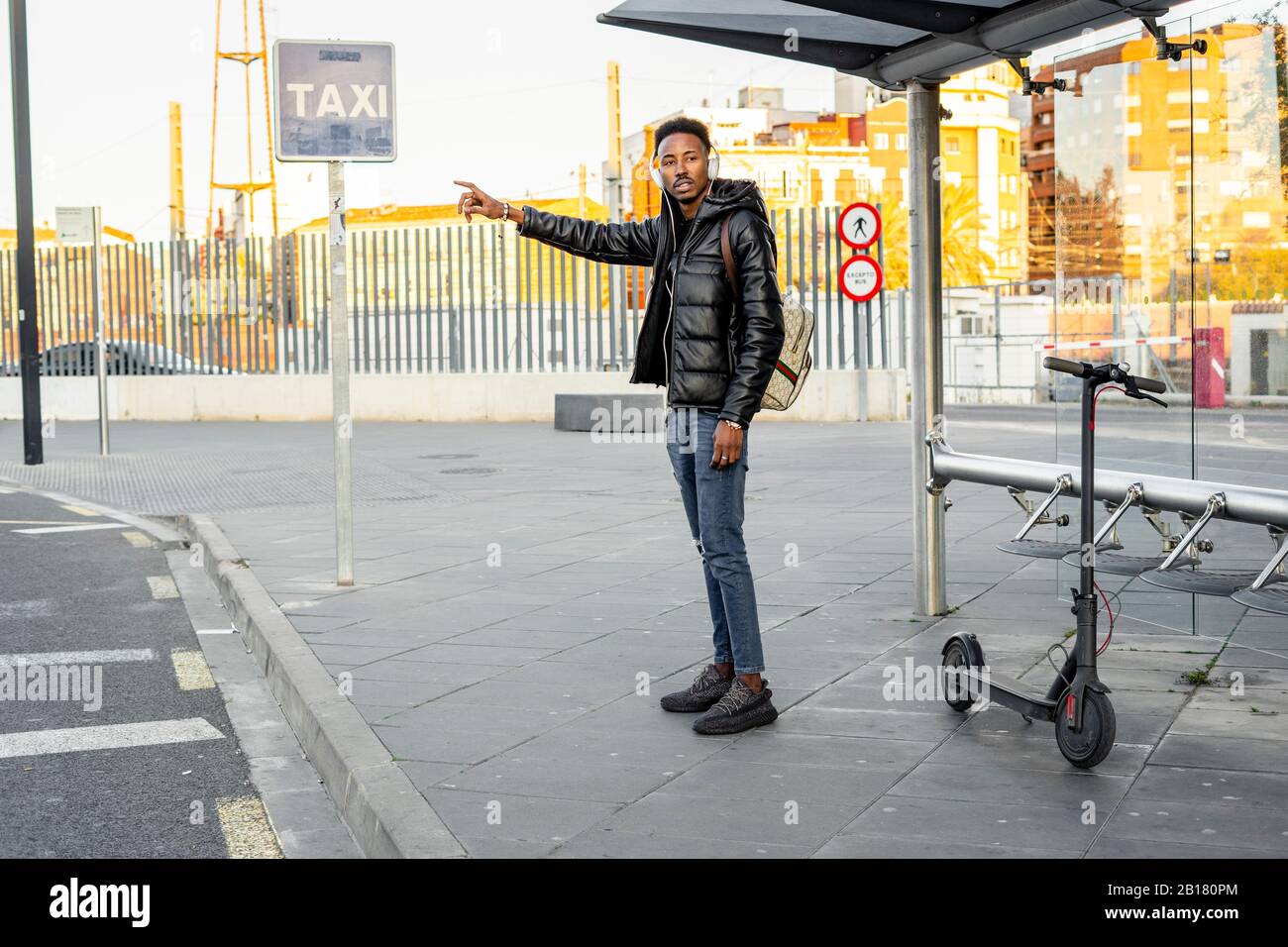 Homme avec casque et e-scooter à l'arrêt de bus Banque D'Images