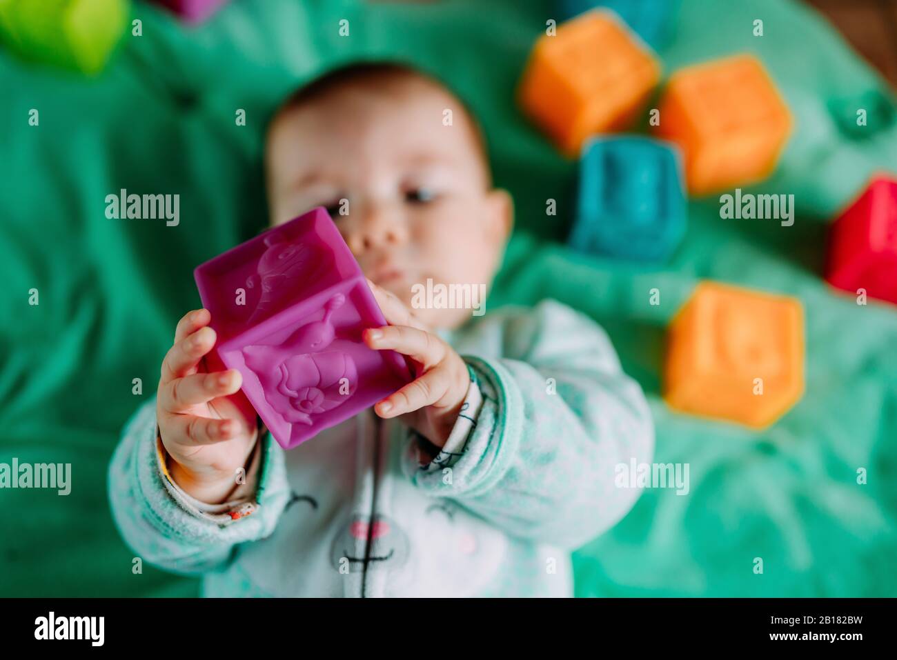 Les Mains De Bebe Tenant Le Jouet Cube En Caoutchouc Violet Gros Plan Photo Stock Alamy