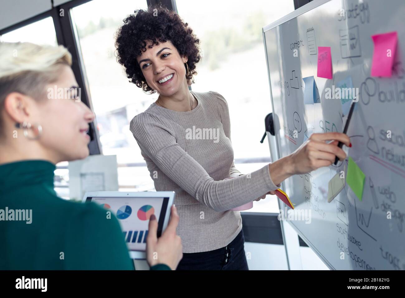Les femmes d'affaires sur un tableau de conférence, présentant des idées pour une optimisation de Search Engine Banque D'Images