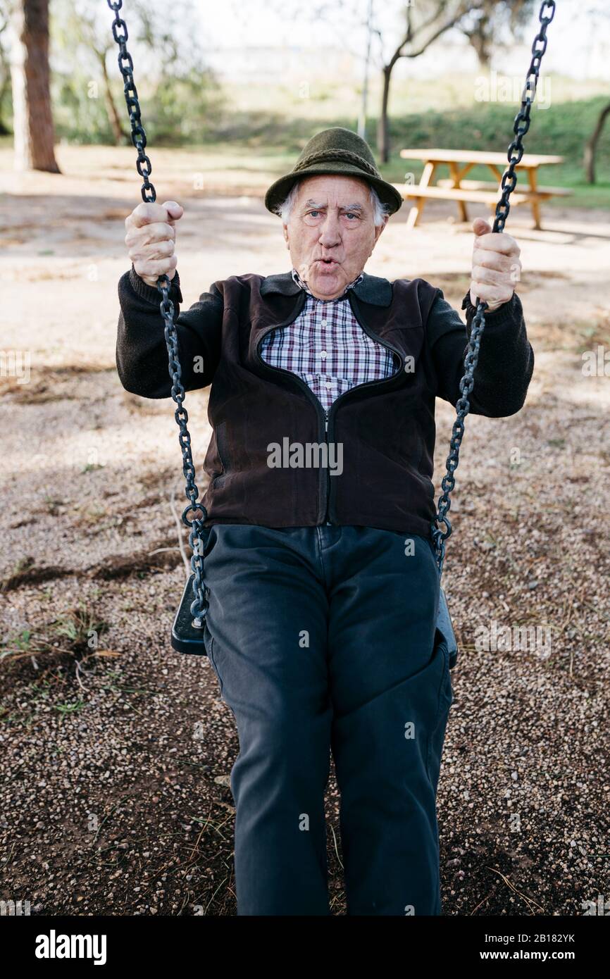 Un vieil homme qui s'est balançé sur le terrain de jeux dans le parc Banque D'Images