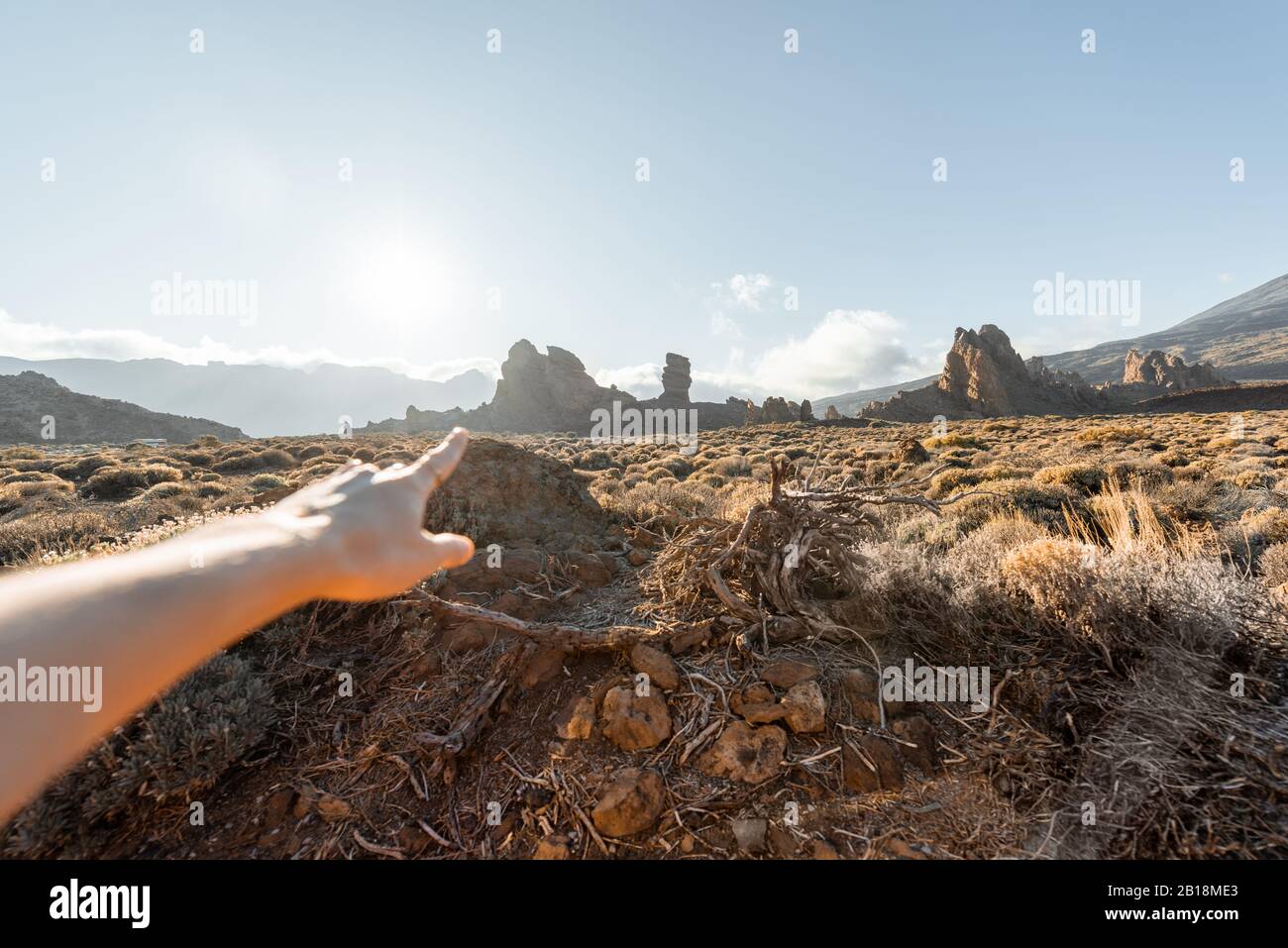 Femme pointant à la main sur les montagnes volcaniques pendant un coucher de soleil, l'image se focalise sur l'arrière-plan Banque D'Images