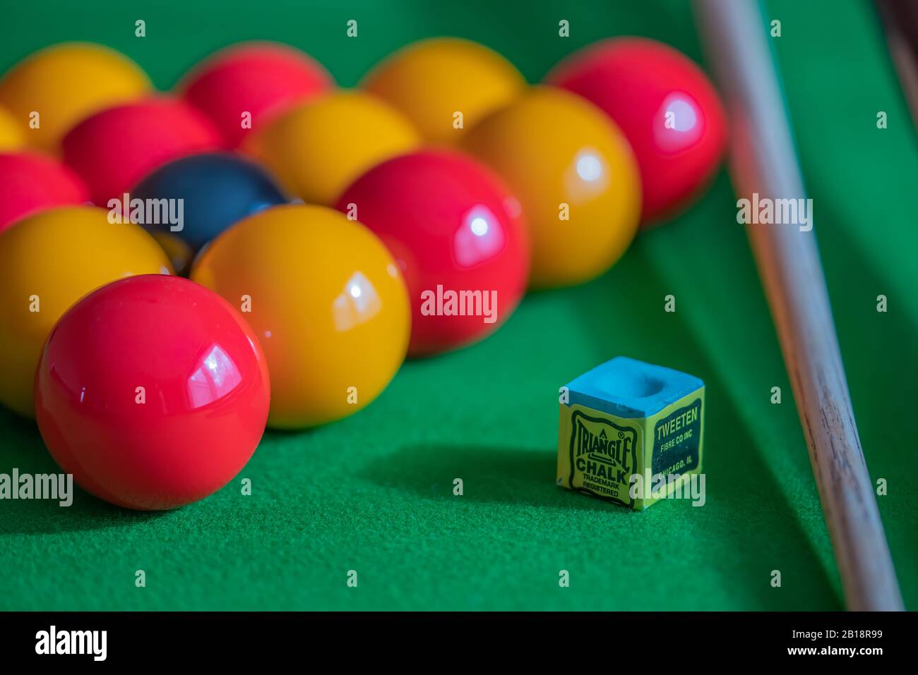 26 gros plan et sélection de la mise au point sur la craie bleue de repère sur une table de billard avec des boules hors foyer configurées dans un triangle en arrière-plan Banque D'Images