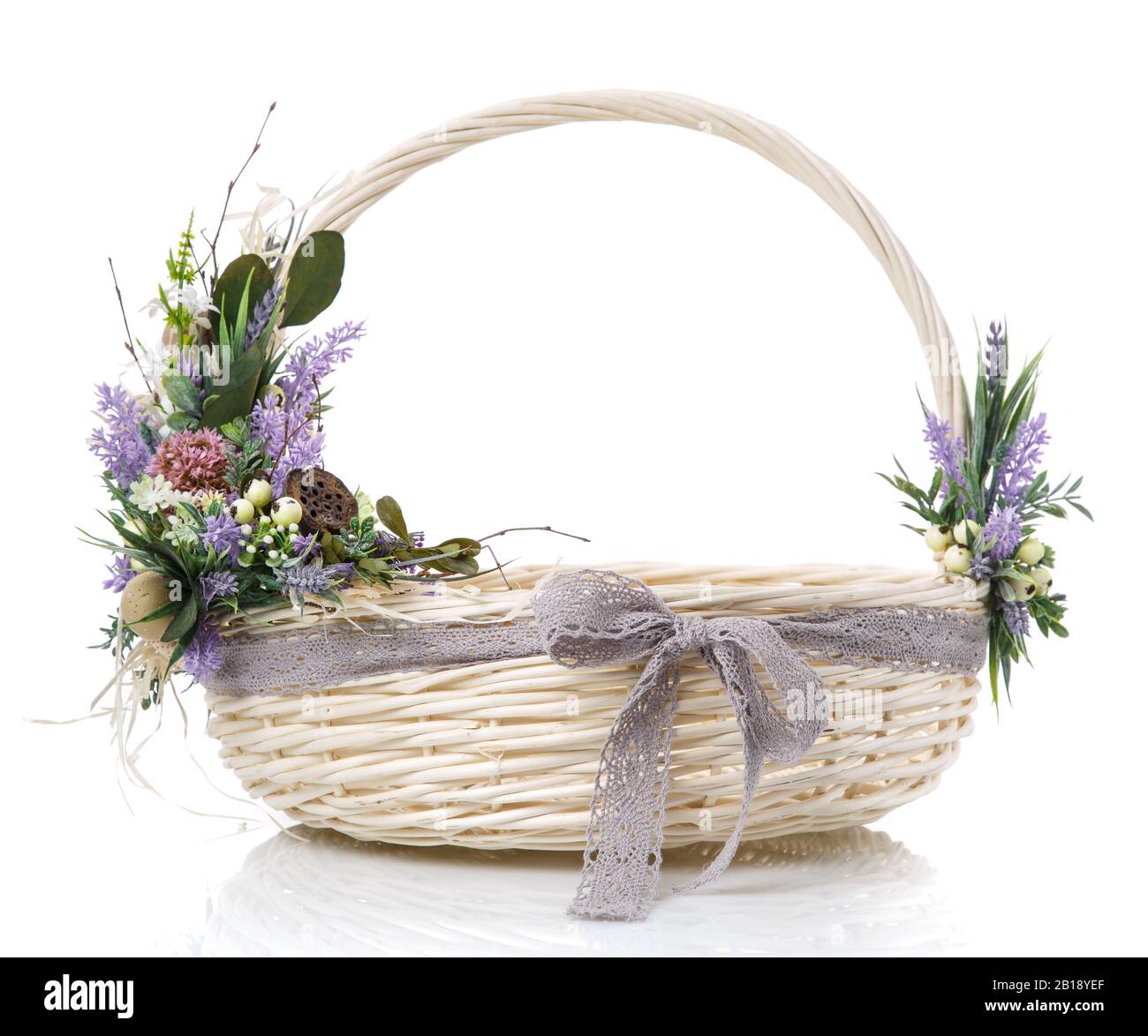 Panier en osier naturel avec fleurs et rubans. Isolé sur un fond blanc. Banque D'Images