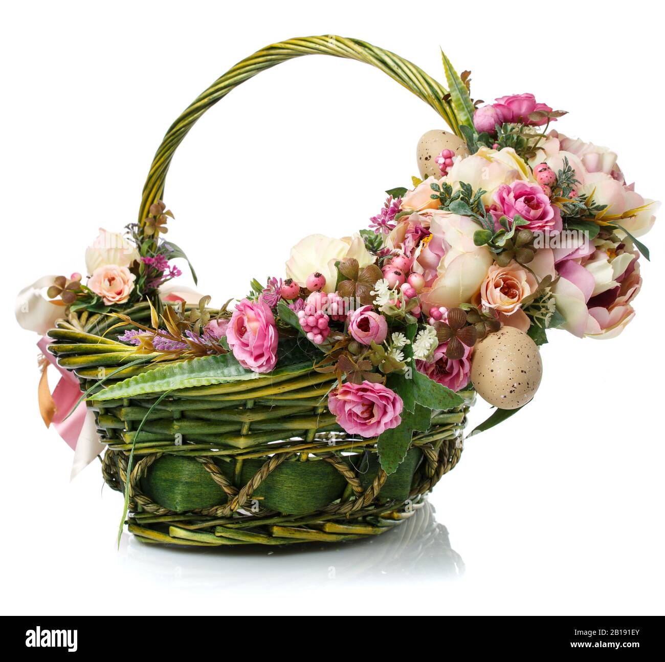 Composition florale avec fleurs, verdure et rubans accrochés sur la poignée d'un panier en osier sur fond blanc Banque D'Images