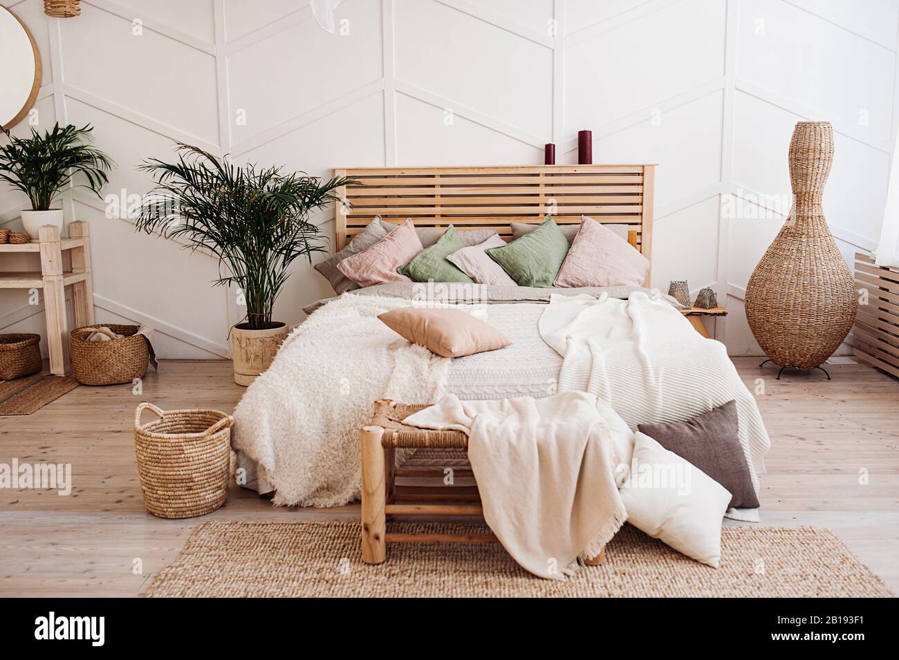 Lit en bois très confortable avec couvre-lit de couleurs pastel, oreillers  de teintes poudreuses et couverture de couleurs délicates. Chambre élégante  de style Boho Photo Stock - Alamy