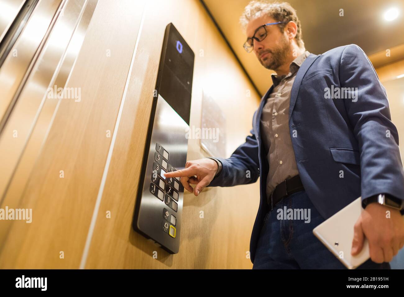 Gros plan sur l'homme d'affaires en appuyant sur le bouton du panneau de commande du troisième étage dans l'ascenseur. Banque D'Images