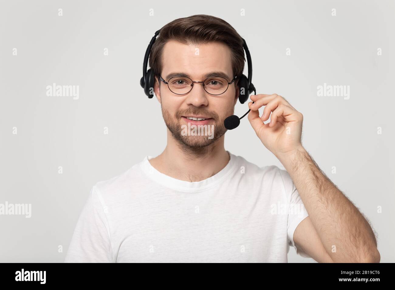 Beau jeune homme portant un casque sans fil bluetooth avec microphone. Banque D'Images