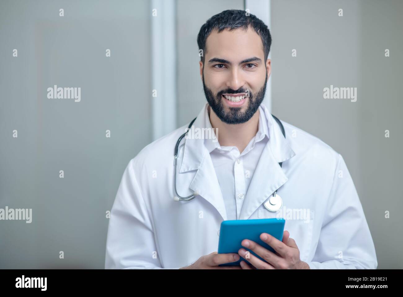 Médecin mâle dans un peignoir blanc souriant et se sentant bien Banque D'Images