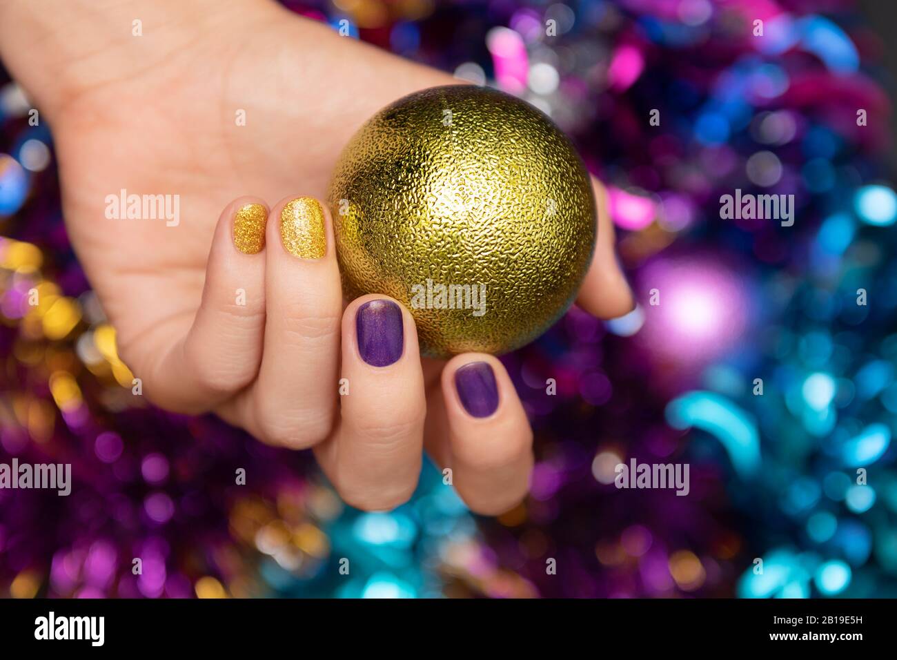 Belle main féminine avec motif clou de noël violet. Banque D'Images