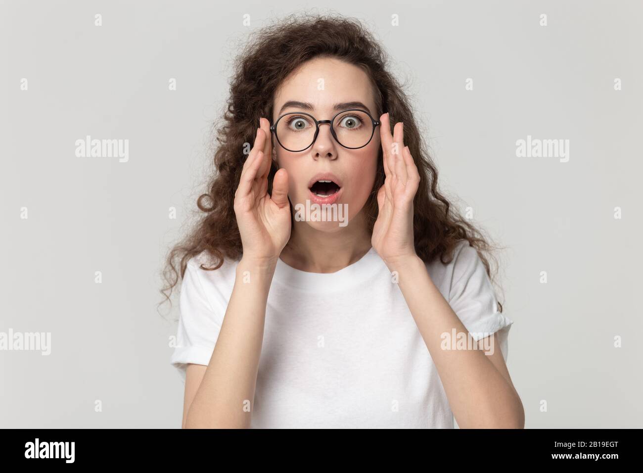 Une jeune femme a été surprise par la mauvaise surprise dans les lunettes en regardant de près l'appareil photo. Banque D'Images