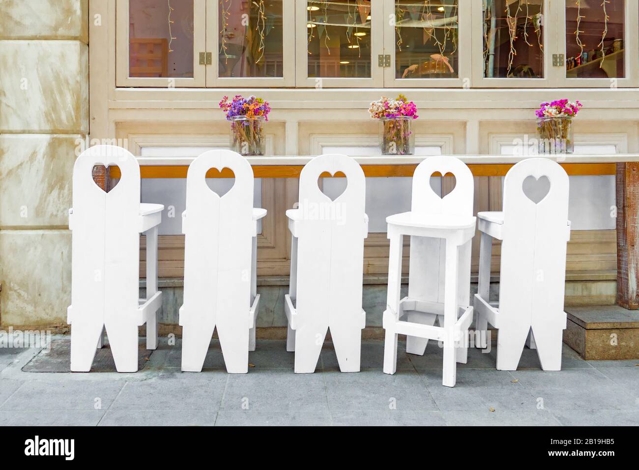 Concept de diversité : six chaises blanches en bois près de la table au décor simple. Unique et autres. Singularité et autres. Accueil backgroud. Occasion familiale. Invitation à l'événement de la vie Banque D'Images
