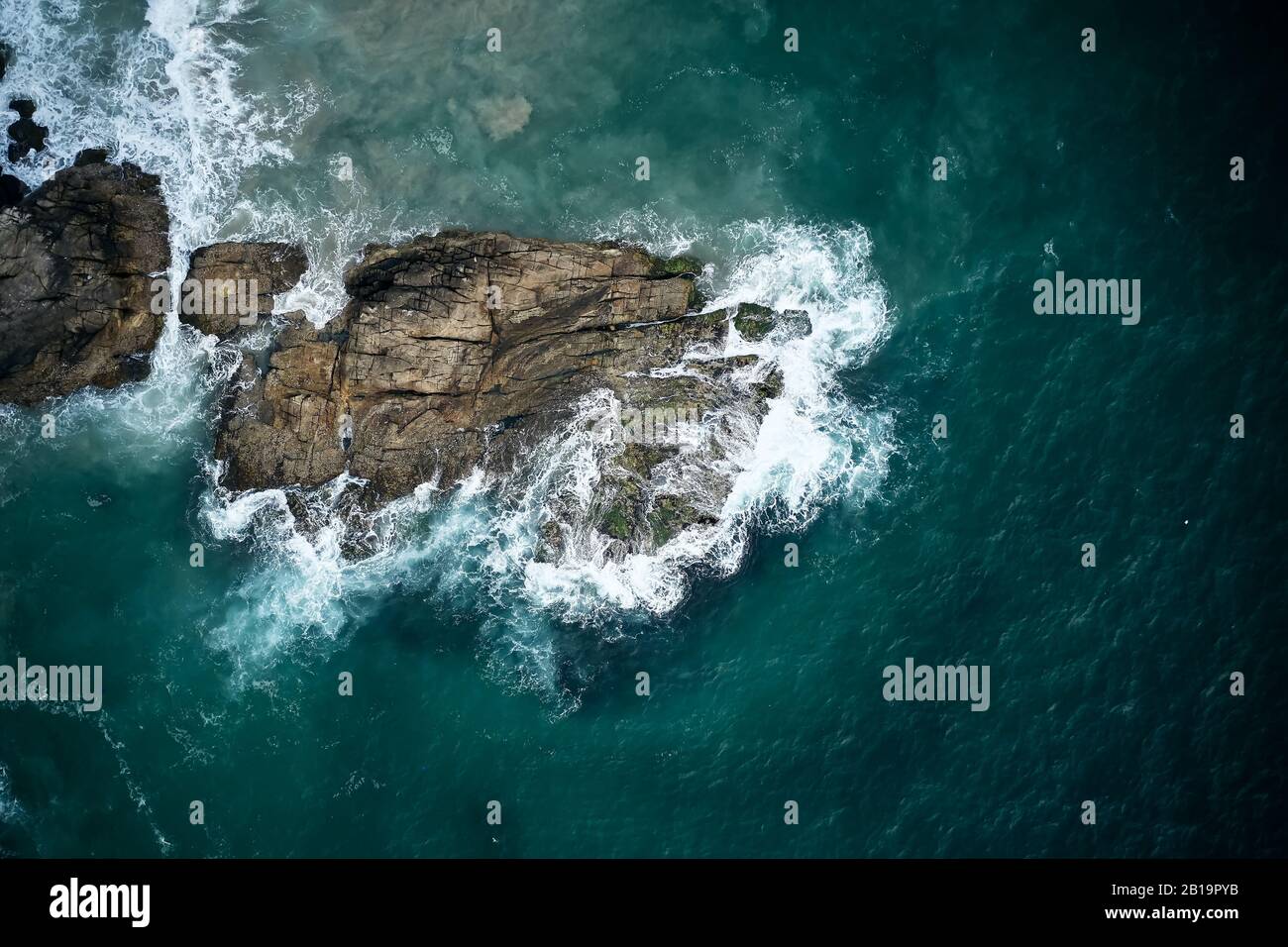 Vue aérienne sur les vagues de l'océan azure sur les rochers. Kerala, Inde. Banque D'Images