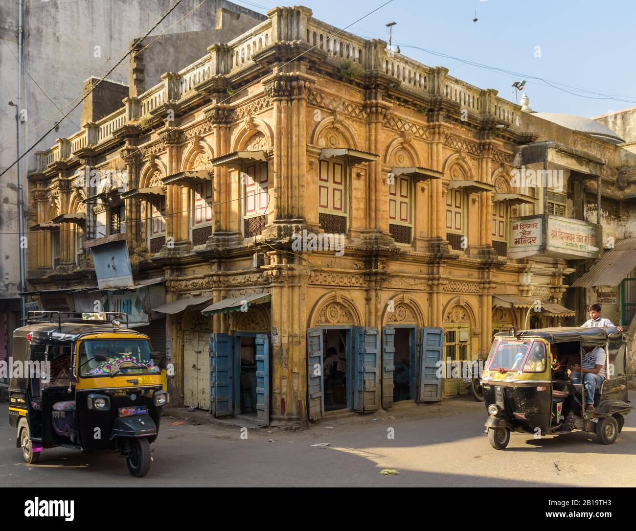 Junagadh, Gujarat, Inde - décembre 2018 : un bel édifice jaune avec des fenêtres à arcades et des portes en bois vintage dans l'ancien marché. Banque D'Images