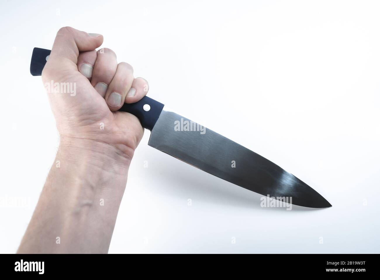 Main tenant grand couteau de cuisine avec intention craineuse sur fond blanc Banque D'Images